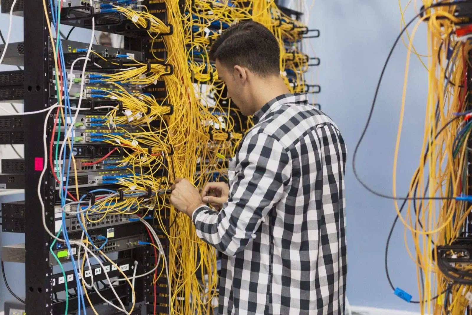 Technicien raccordant une baie réseau lors d'un déploiement de téléphonie IP